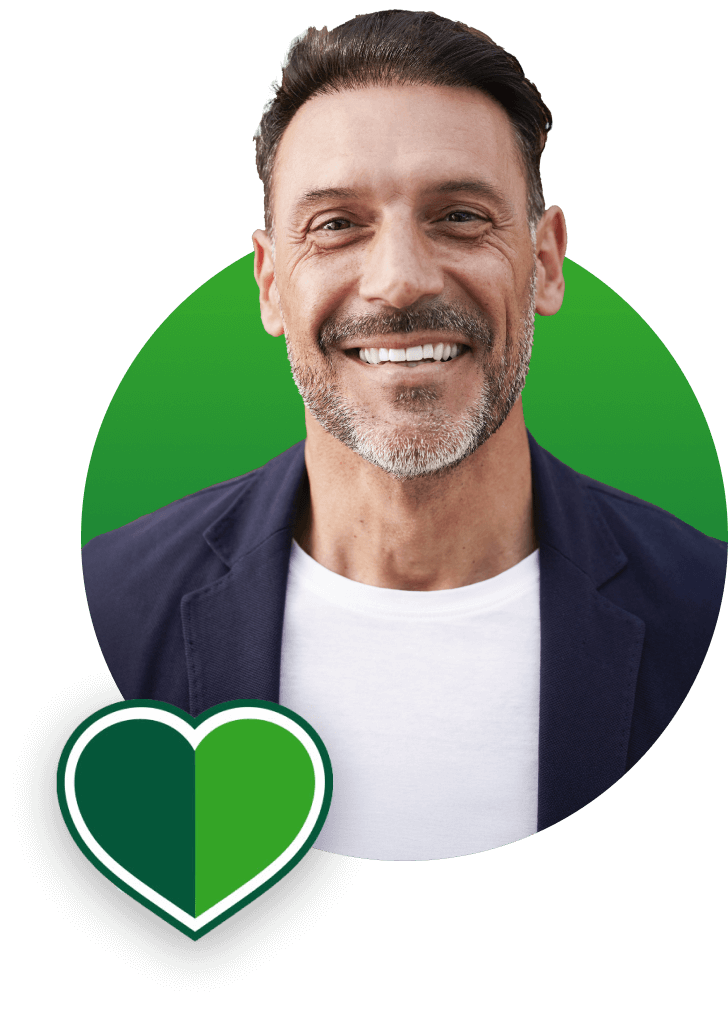 Smiling man in a navy blazer and white shirt against a green circular background, with a green heart icon in the corner.