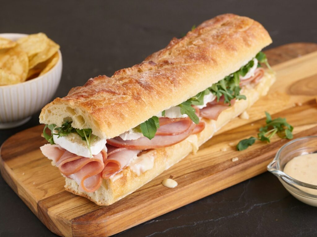 A sub sandwich atop a wooden cutting board.