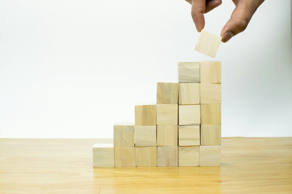 Someone stacking wooden blocks to form a staircase that represents profit.
