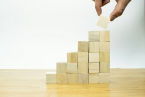 Someone stacking wooden blocks to form a staircase that represents profit.