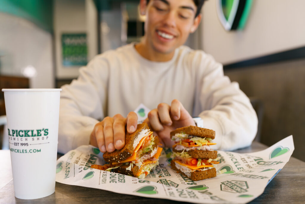 A customer digs into a delicious Mr. Pickle’s sandwich.